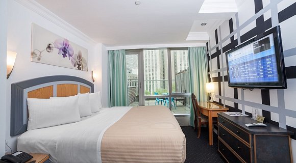 Photo 1 of Deluxe King Room with Balcony with a king sized bed, view of the lower west side, and all the standard amenities.